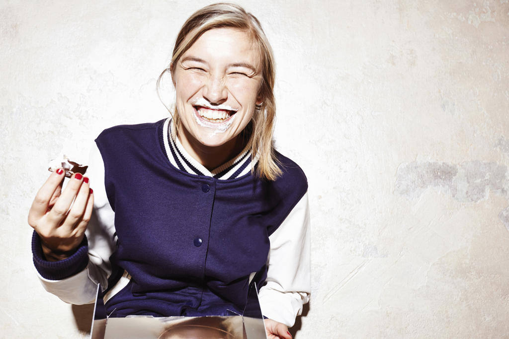 STUDIO SHOT OF YOUNG WOMAN EATING CHOCOLATE MARSHMALLOWS