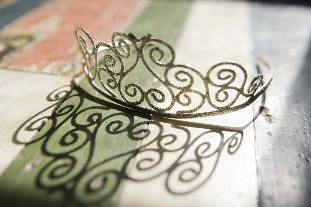 A DELICATE FILIGREE CROWN RESTING ON A RUSTIC WOODEN SURFACE PAINTED WITH THE COLORS OF THE ITALIAN FLAG