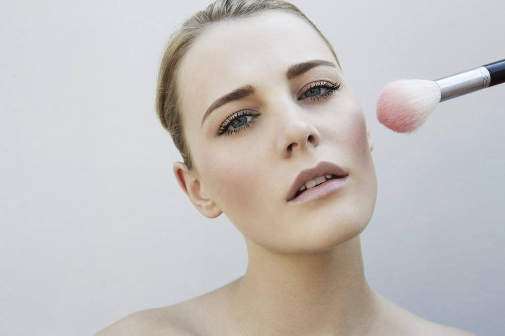 MAKEUP ARTIST APPLYING BLUSH ON A MODEL'S CHEEK