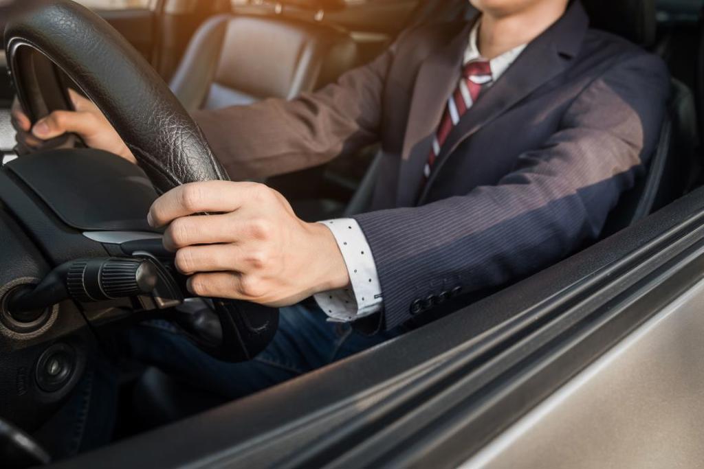 PORTRAIT OF A YOUNG HANDSOME BUSINESSMAN DRIVING A LUXURY SPORTS CAR