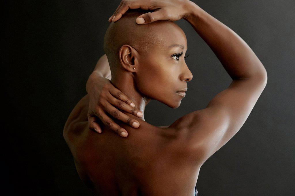 AFRICAN AMERICAN WOMAN HOLDING HER BALD HEAD