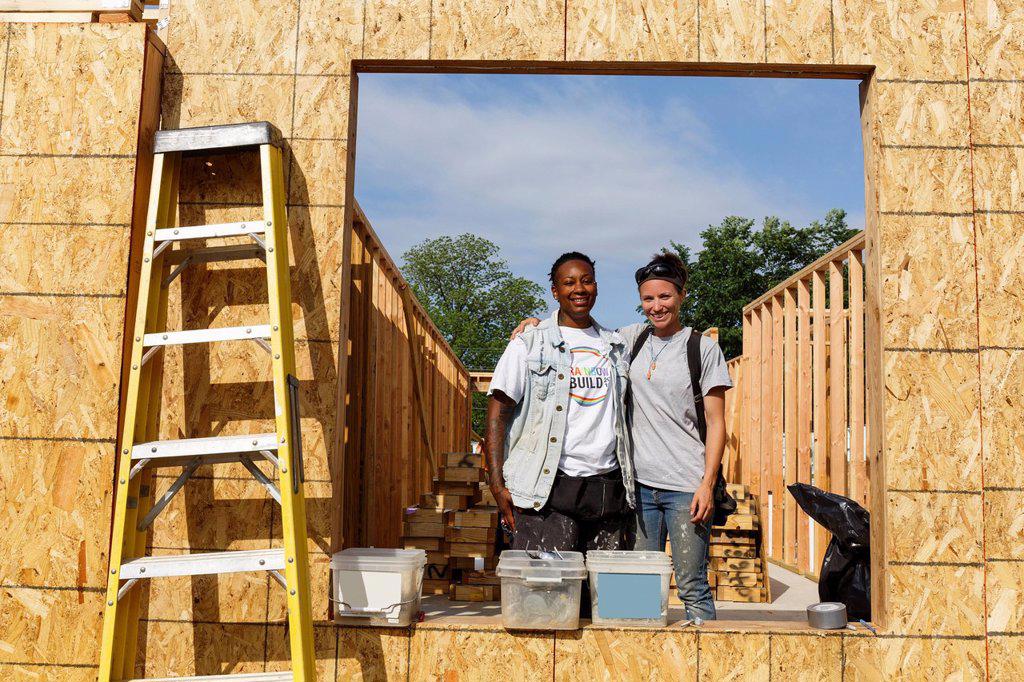 VOLUNTEERS BEHIND WINDOW FRAME AT CONSTRUCTION SITE