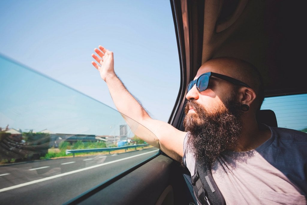 BEARDED MAN STICKING HAND OUT OF CAR WINDOW ON HIGHWAY, GARDA, ITALY