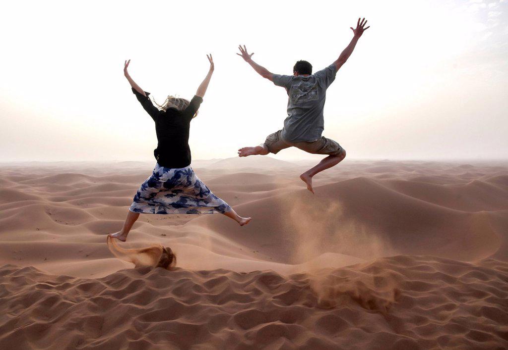 PEOPLE JUMP IN THE CHEGAGA DUNES IN THE SAHARA DESERT IN MOROCCO