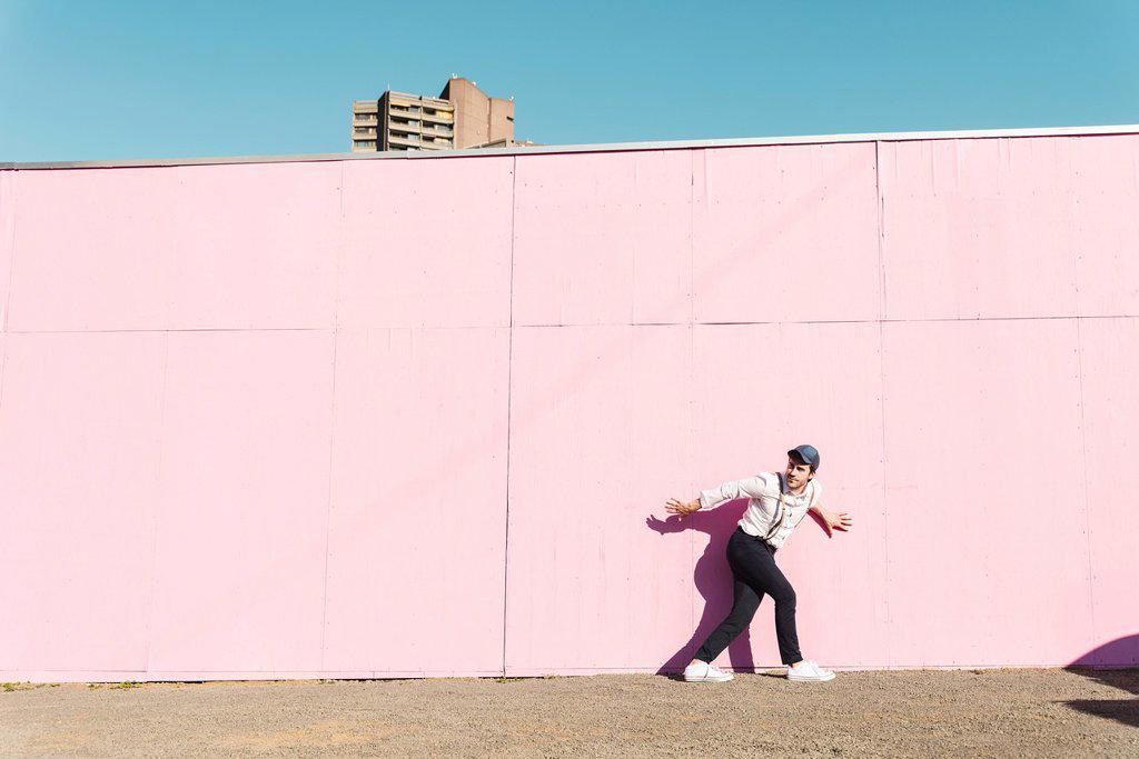 YOUNG MAN IN FRONT OF PINK CONSTRUCTION BARRIER, TRYING TO ESCAPE