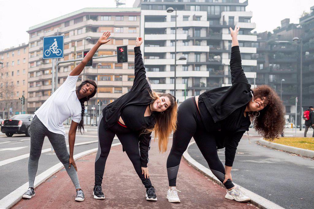 THREE SPORTIVE YOUNG WOMEN TRAINING IN THE CITY