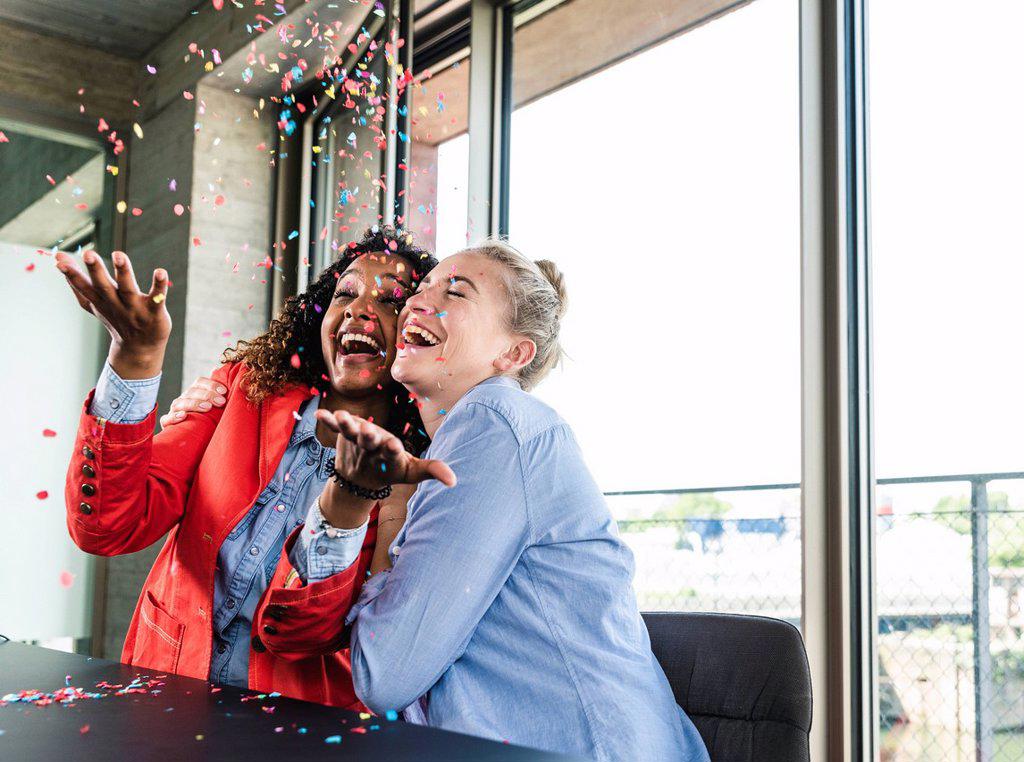 YOUNG BUSNIESSWOMEN CELEBRATING SUCCESS, THROWING CONFETTI