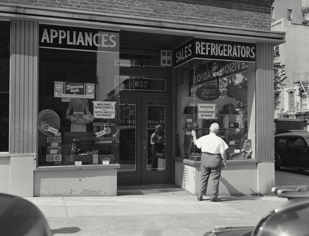 EXTERIOR OF HOME APPLIANCE STORE WITH MAN CHECKING WINDOW OF FRONT DISPLAY