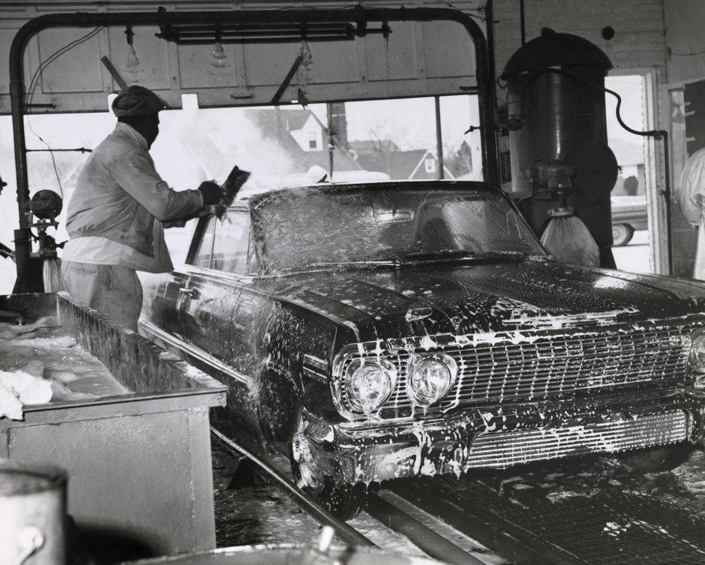 SIDE PROFILE OF AN ATTENDANT WASHING A CAR