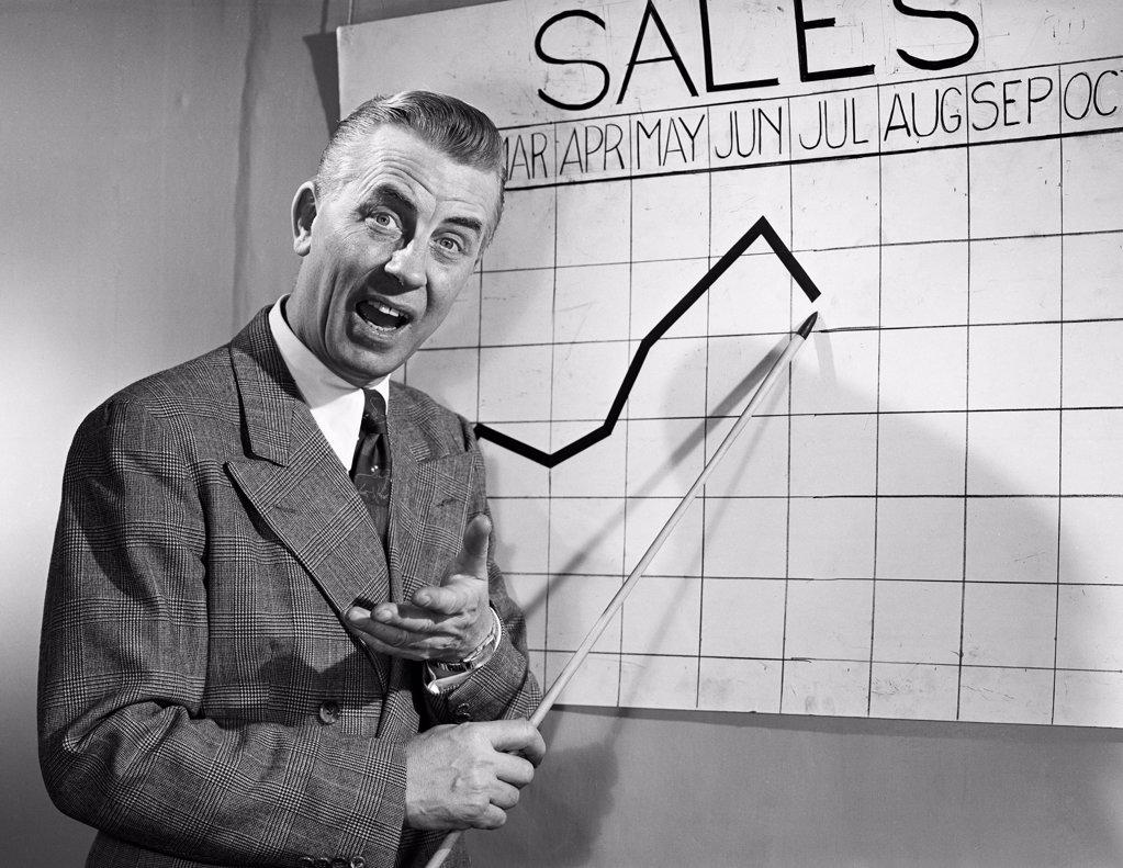 BUSINESSMAN POINTING AT SALES CHART