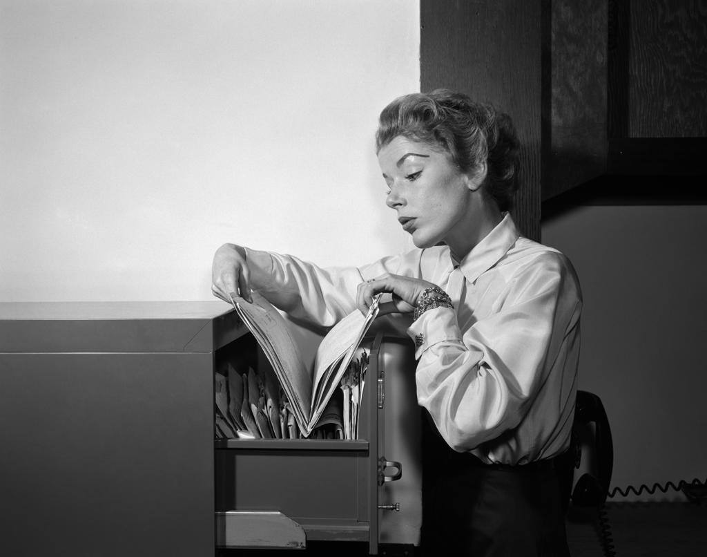 1950S Woman Working In Office Looking Through Files In File Cabinet