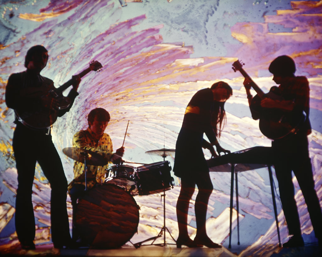 ANONYMOUS SILHOUETTED TEEN ROCK BAND GIRL ON KEYBOARD WITH GUITARS AND DRUMS SWIRLY BLUE PINK PSYCHEDELIC BACKGROUND