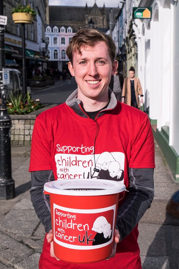 A VOLUNTEER COLLECTING DONATIONS FOR CHILDREN WITH CANCER UK.