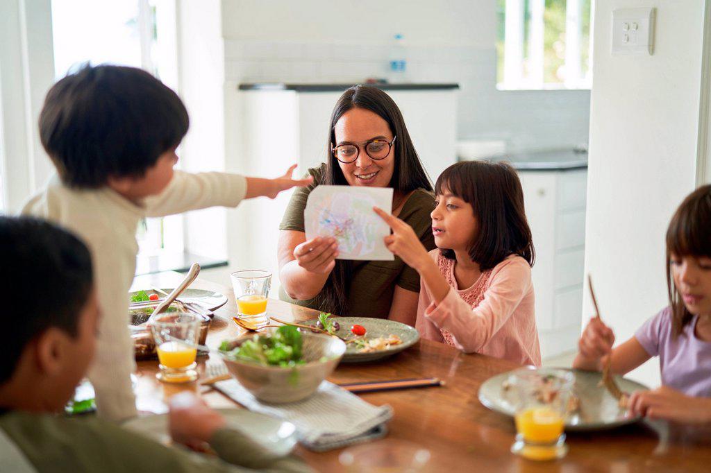 MOTHER AND KIDS EATING LUNCH AT DINING TABLE