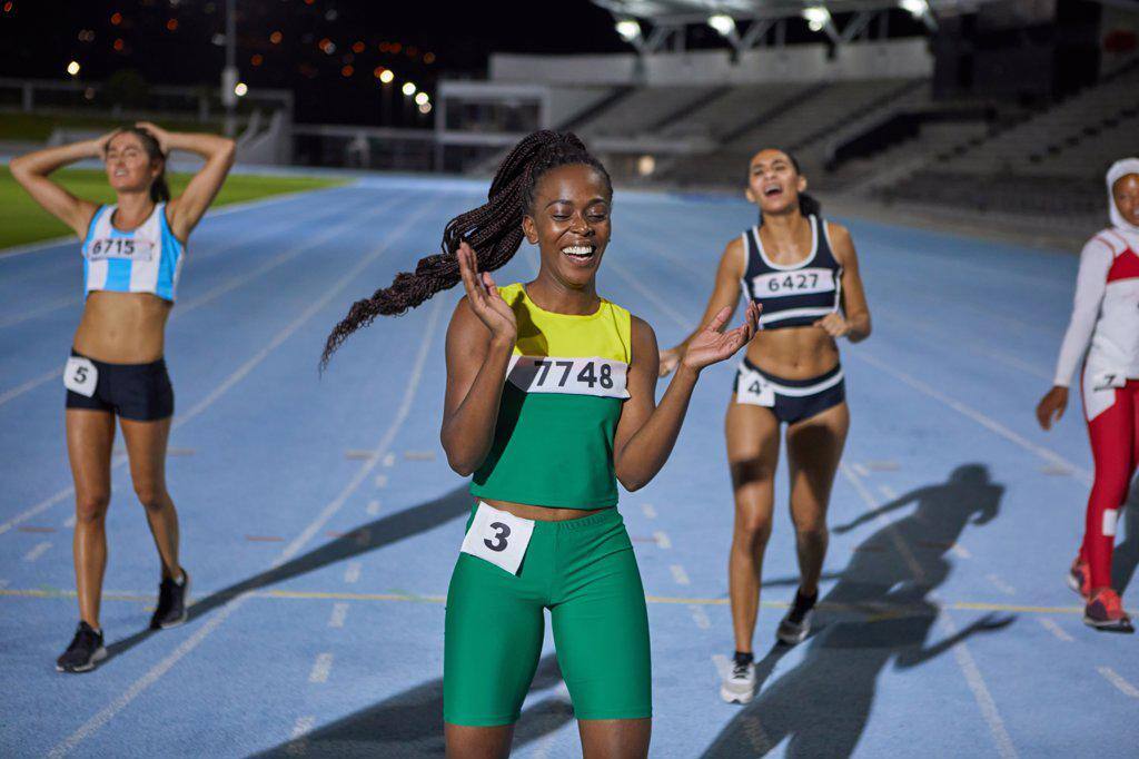 Happy female track and field athlete celebrating after race on track