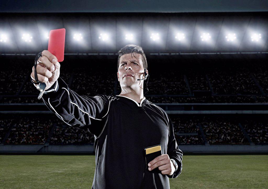 REFEREE FLASHING RED CARD ON SOCCER FIELD