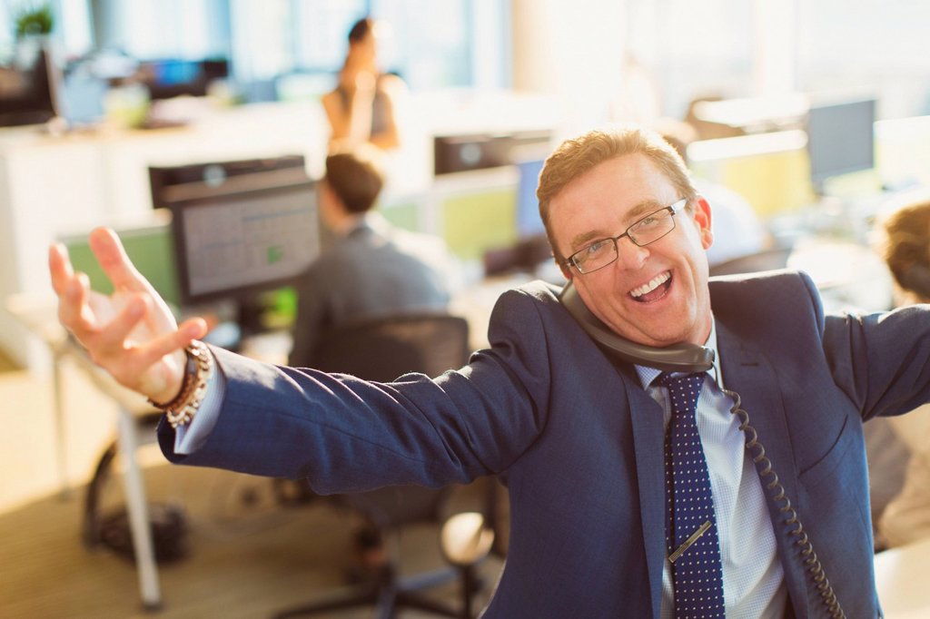 PORTRAIT OF EXUBERANT BUSINESSMAN WITH ARMS OUTSTRETCHED TALKING ON TELEPHONE