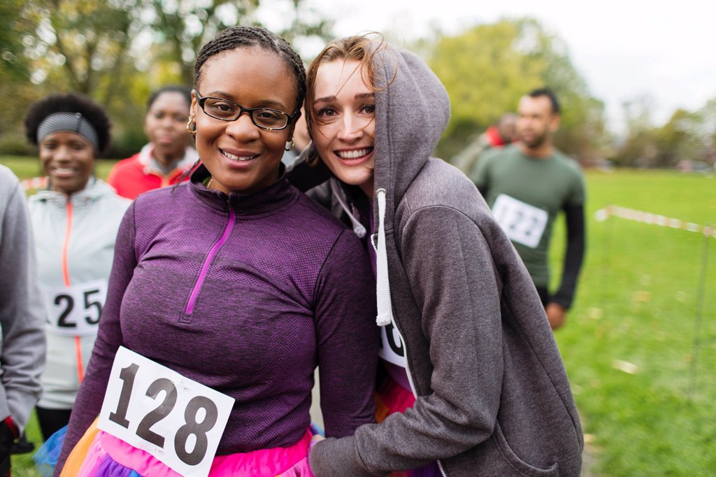 SMILING, CONFIDENT FEMALE RUNNERS AT CHARITY RUN IN PARK