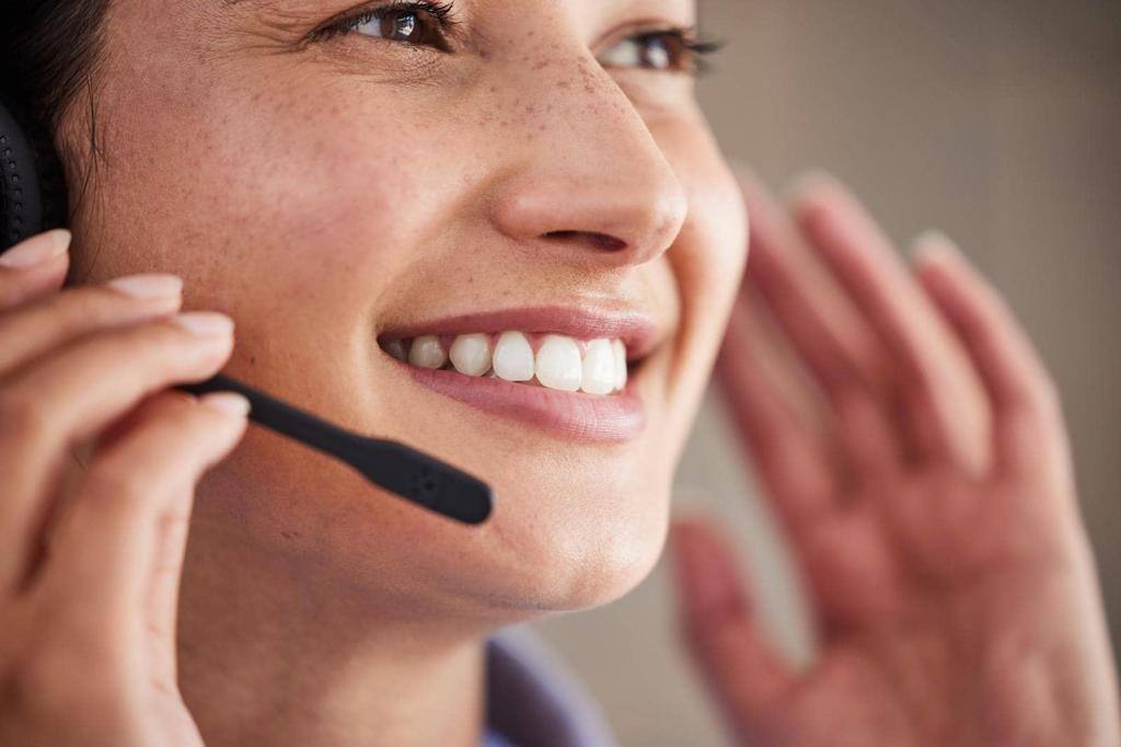 Closeup of young mixed race female call center agent wearing headset and talking to clients customers