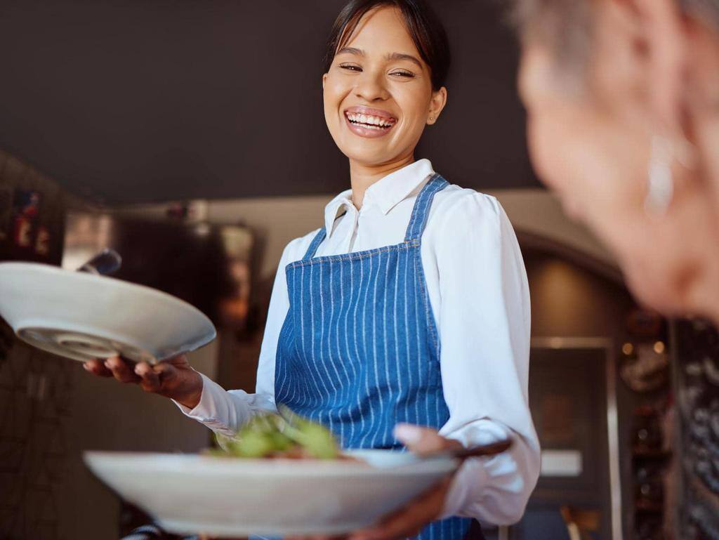 Waitress in a restaurant, serving customer her food, healthy salad and gives service with a smile