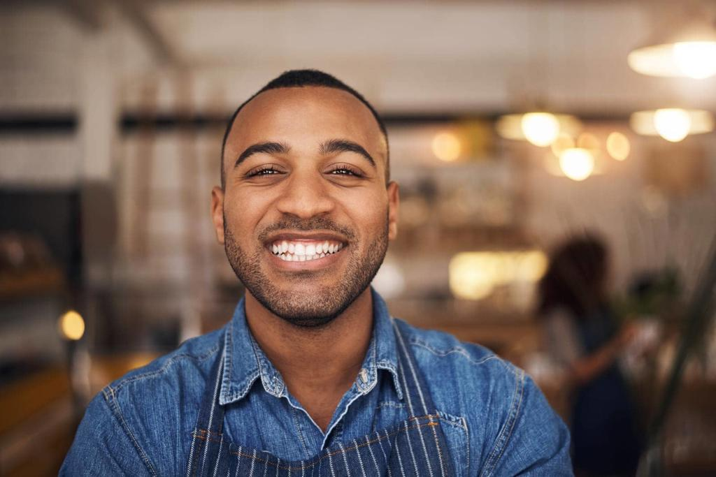 COFFEE SHOP, HAPPY WAITER AND PORTRAIT OF BLACK MAN IN RESTAURANT FOR SERVICE, WORKING AND SMILE IN CAFE