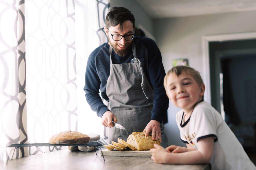 MAN CUTTING A FRESH LOAF OF BREAD FOR LUNCH.