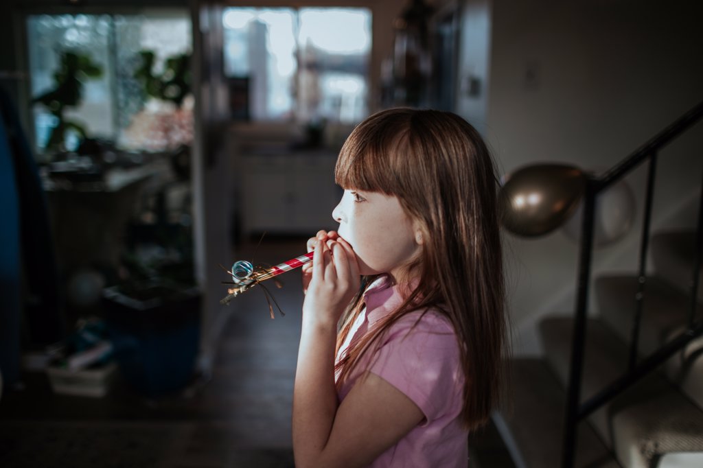 YOUNG GIRL STANDING WITH PARTY FAVOR IN MOUTH