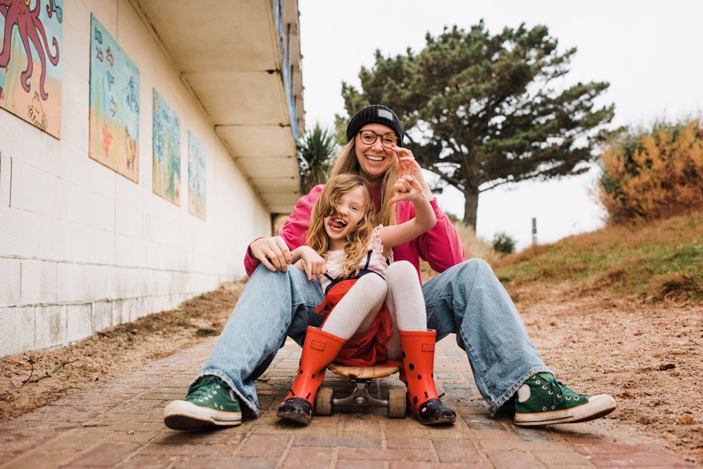 MOTHER AND DAUGHTER ON A SKATEBOARD LAUGHING HAVING FUN