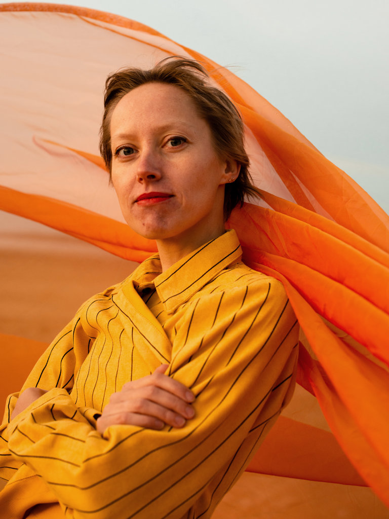 PORTRAIT OF WOMAN WITH ORANGE CLOTH IN DESERT