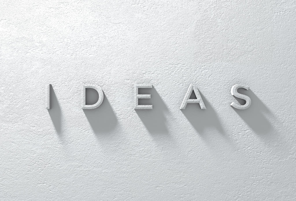 A 3D RENDERED SIGN OF THE WORD IDEAS ON A DRAMATICALLY LIT WHTE TEXTURED WALL
