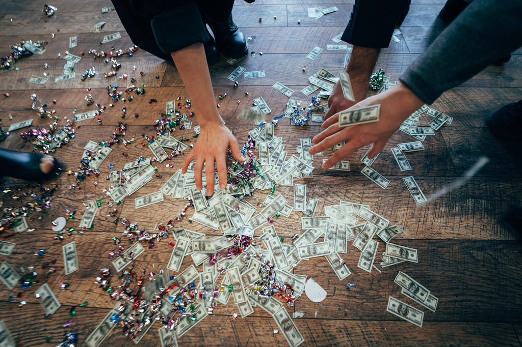 Several pairs of hands pick up dollar bills from the floor Several pairs of hands pick up dollar bills from the floor