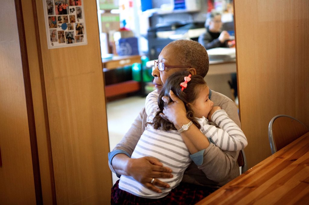 VOLUNTEER RETIREE COMFORTS A CHILD AT INTERGENERATIONAL PROJECT SET UP IN A KINDERGARTEN AND CRÈCHE IN SWITZERLAND.